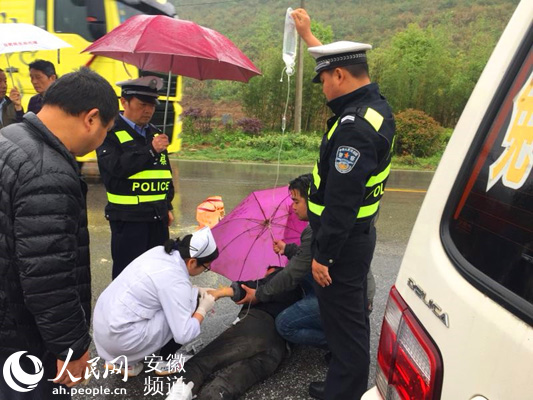 风雨中,安徽泾县交警为车祸伤者撑伞举吊瓶