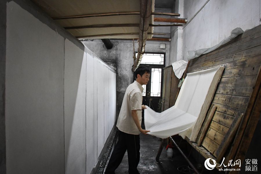 “大國工匠”毛勝利正在進行晒紙，從事晒職工30多年的他每天要“晒”一千張宣紙。周坤  攝