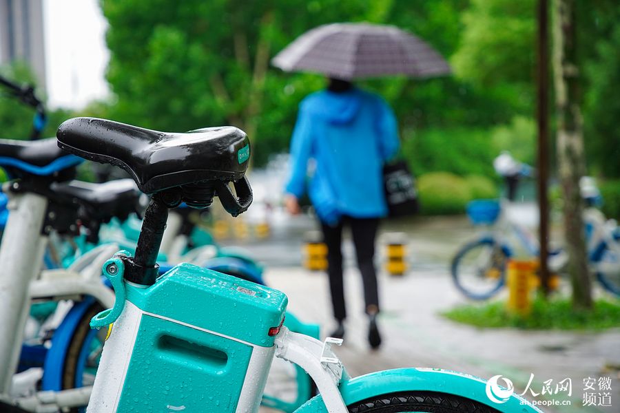 雨中，一位行人路過共享單車點。王曉飛攝