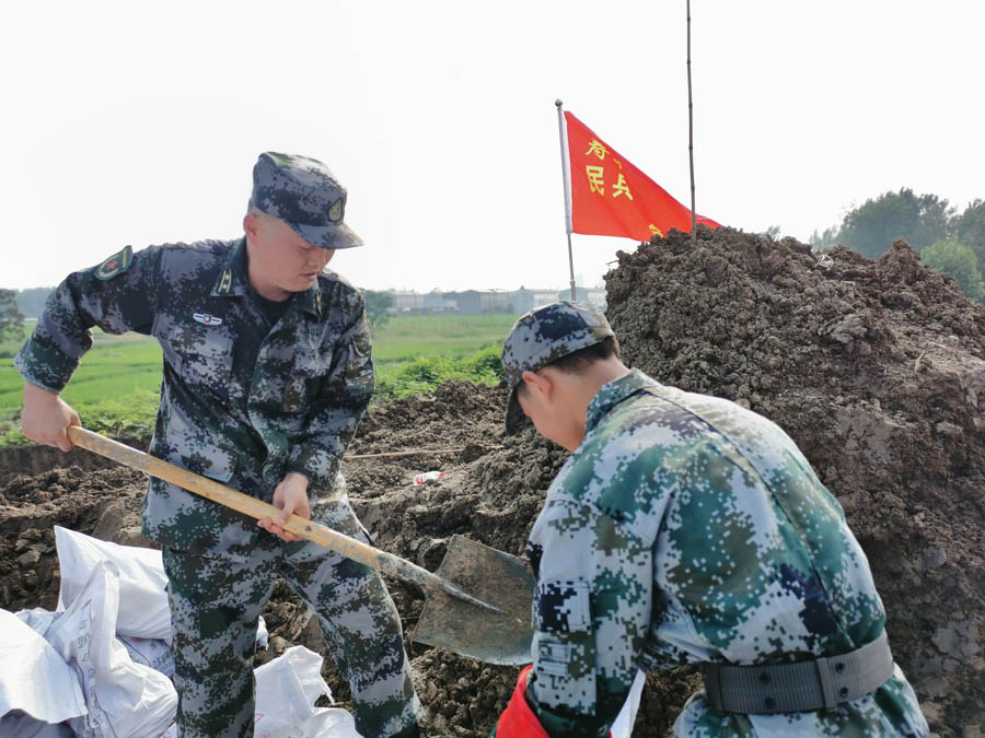 王峰（左一）正在與民兵一起鏟土抗洪