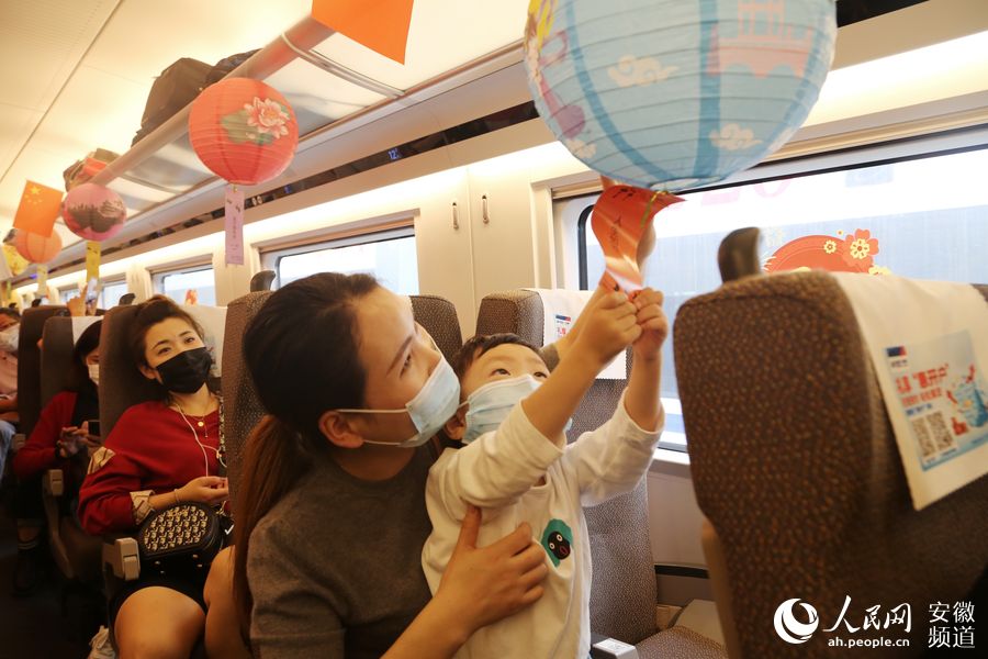 G266次列車上，一位母親正帶著孩子觀賞花燈。梁浩然 攝