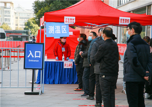 上百名小区居民排列有序,依次进行测温,登记,然后在穿著防护服的专业