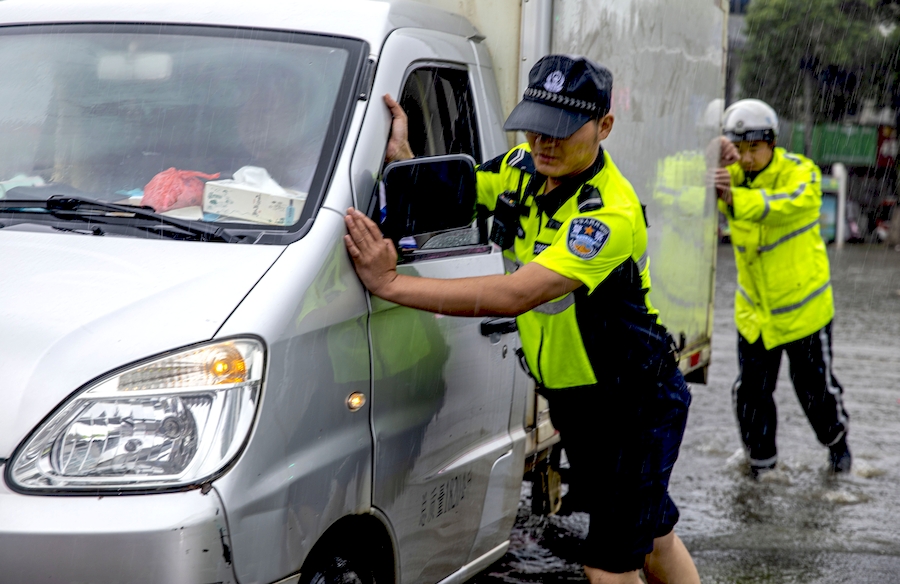 廬江交警在積水中幫助受困車主推車。左學長攝