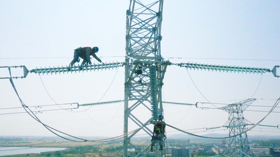 電力工人正在50多米高的鐵塔上進行放緊線施工作業。滁州供電公司供圖