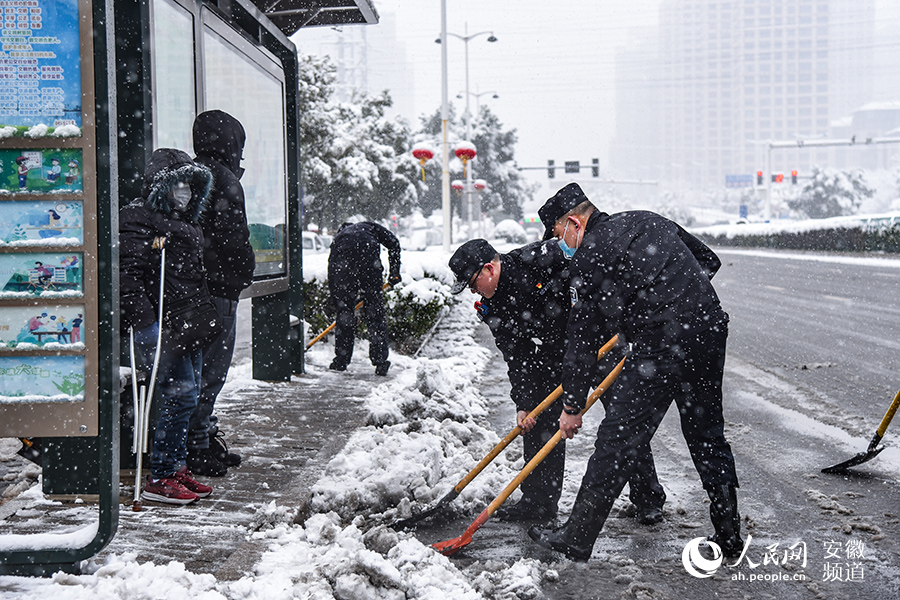 合肥市荷葉地派出所民警正在配合社區工作人員清理道路積雪。人民網 李希蒙攝