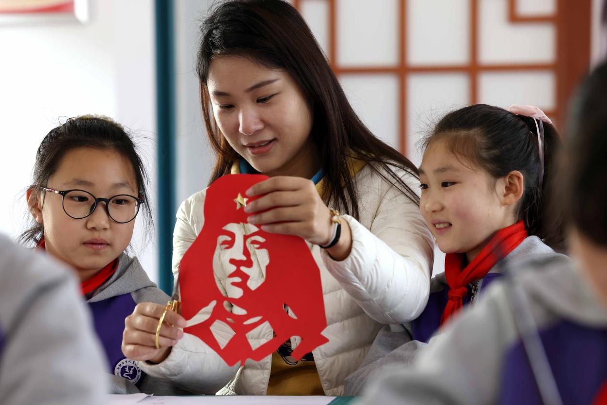 2022年3月4日，在合肥市少兒藝術學校，老師為孩子們教授創作“雷鋒”剪紙作品。解琛攝