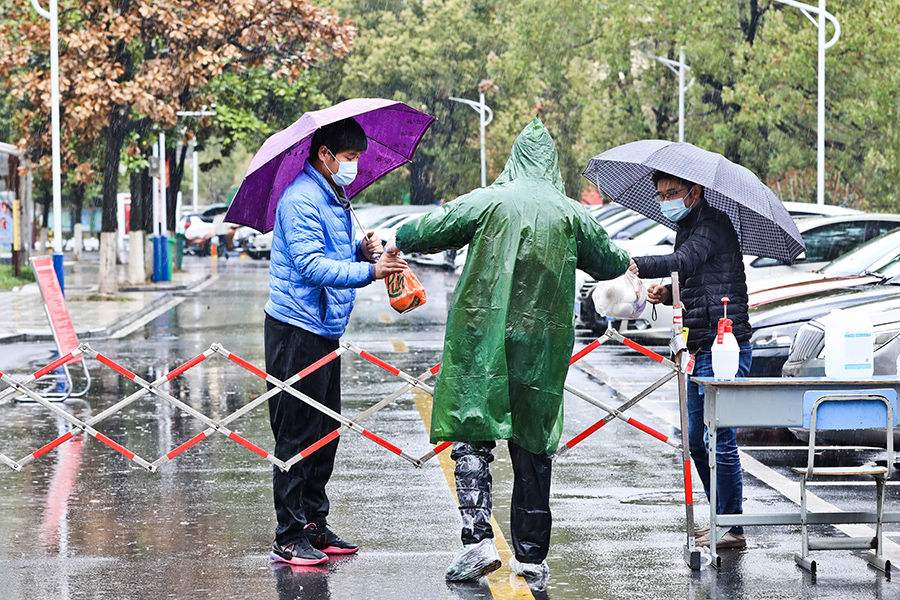 在封控區工作的志願者，腳上裹著膠布，冒雨給百姓送物資。儲燦林攝
