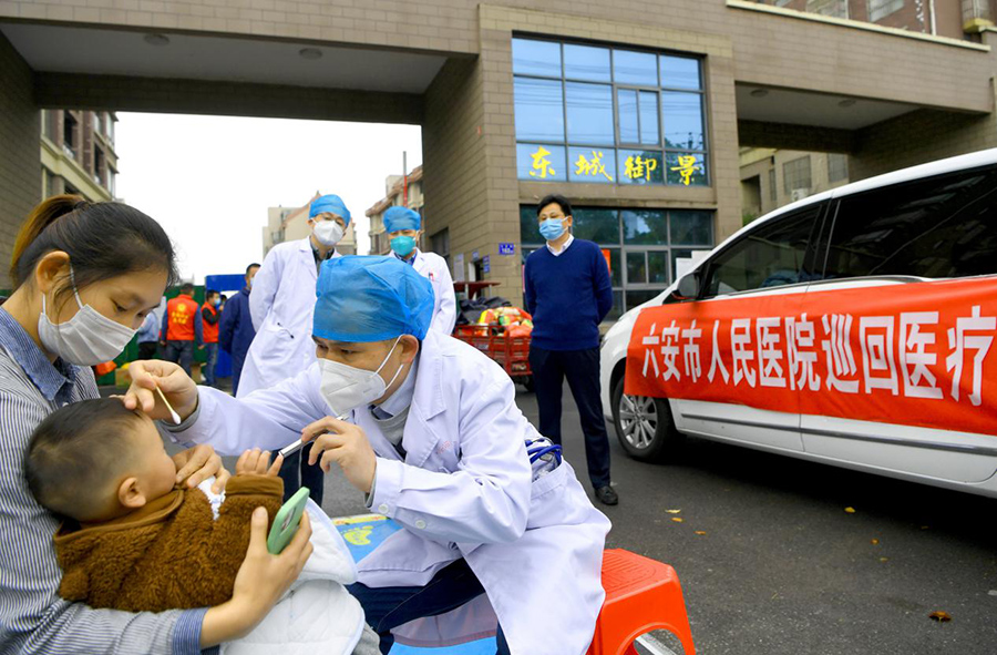 兒科專家馬永利（右一）在六安經濟技術開發區東城御景小區為患兒檢查。陳力攝