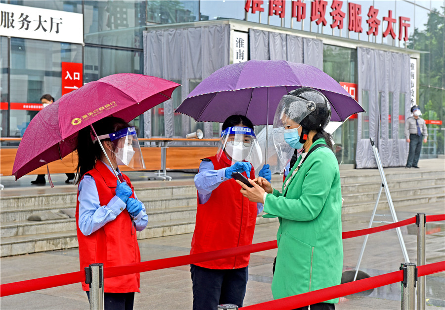 2022年4月25日，安徽省淮南市政務服務大廳恢復窗口服務，志願者檢查進入大廳人員行程碼、健康碼，測量體溫，落實防疫措施。陳彬攝