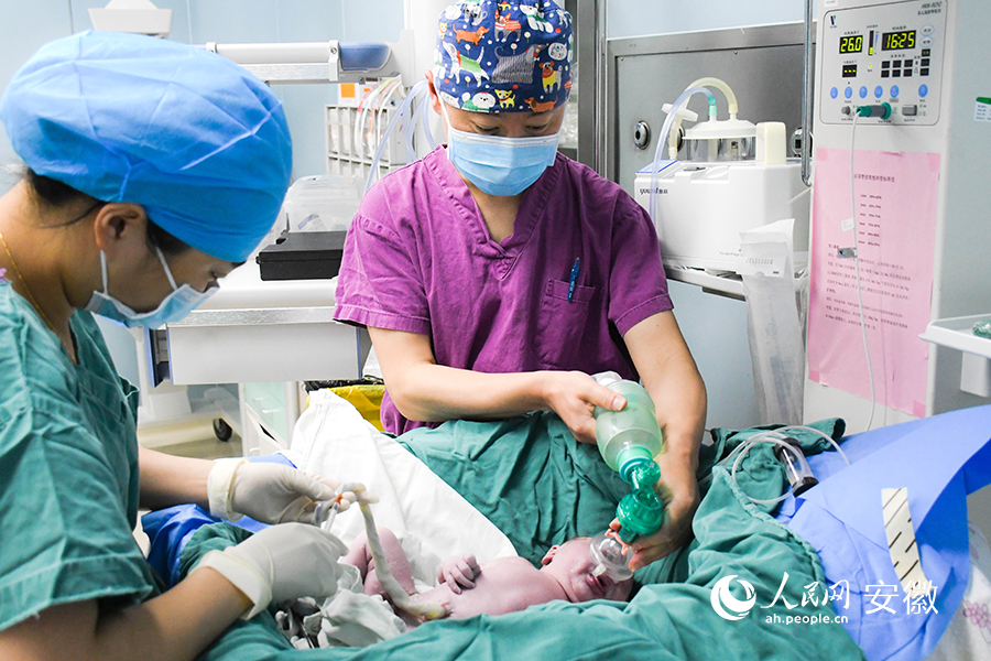 在手術室，男護士楊丙樂（右）正在協助護理新生兒。人民網 周坤攝