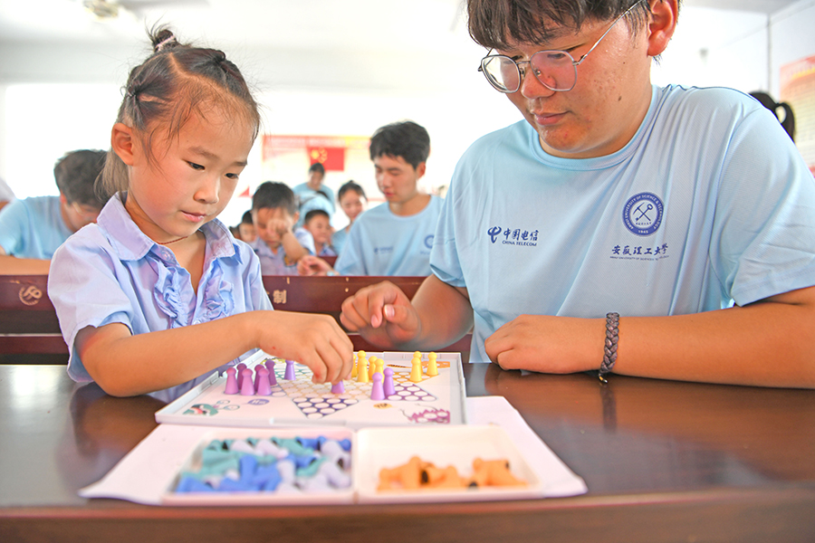 志願者與孩子們一起下棋。陳彬攝