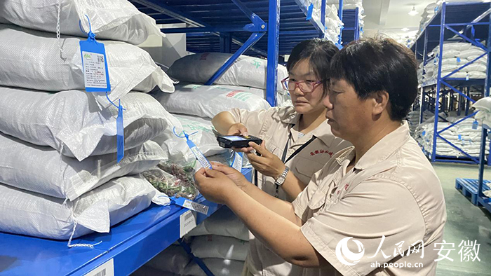 谭艳芳（右一）正和同事核对仓库内中药饮片入库信息。人民网 吕欢欢摄
