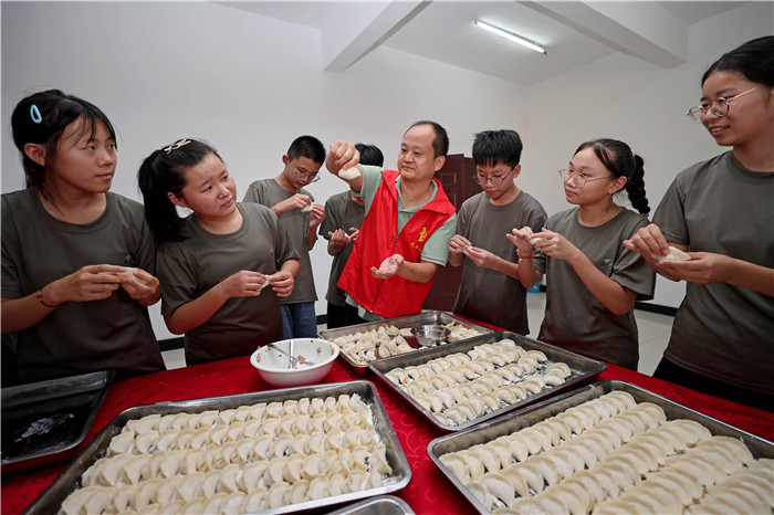 8月6日，志愿者带领参加公益夏令营的孩子们一起包饺子。沈果摄