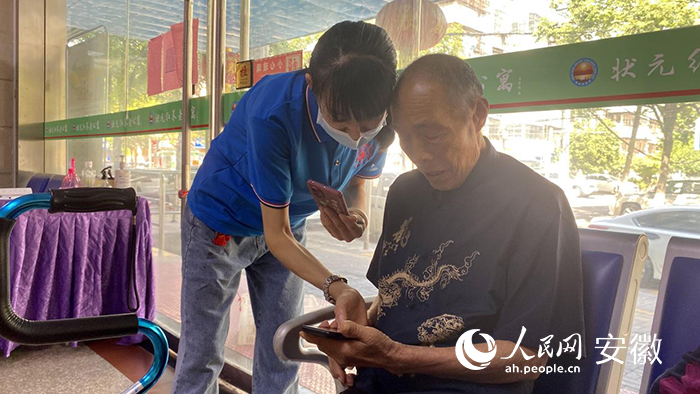 工作人员正在教徐爷爷如何使用智能手机。人民网 吕欢欢摄