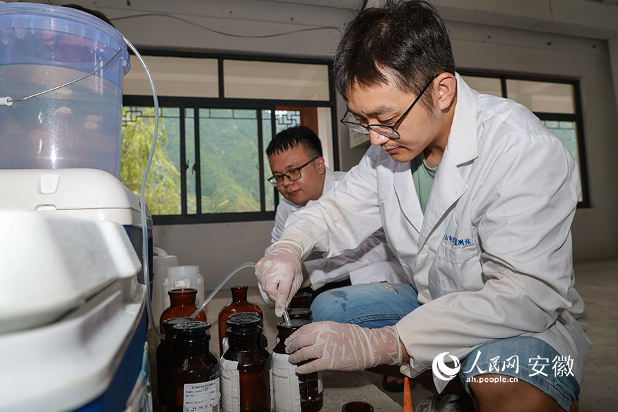 过筛后的水样通过虹吸灌入采样瓶。人民网 张俊摄