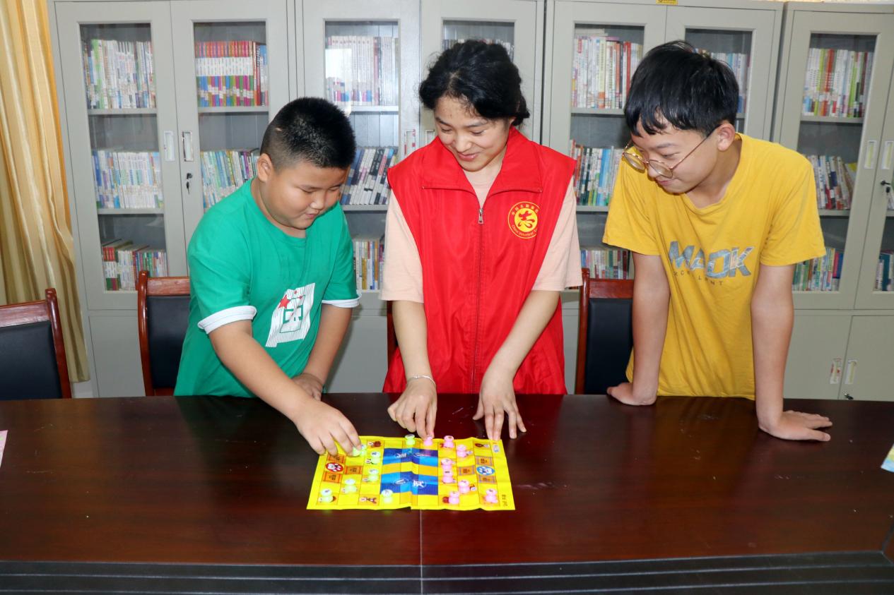 大学生志愿者正在带留守儿童下棋。谯城区牛集镇供图