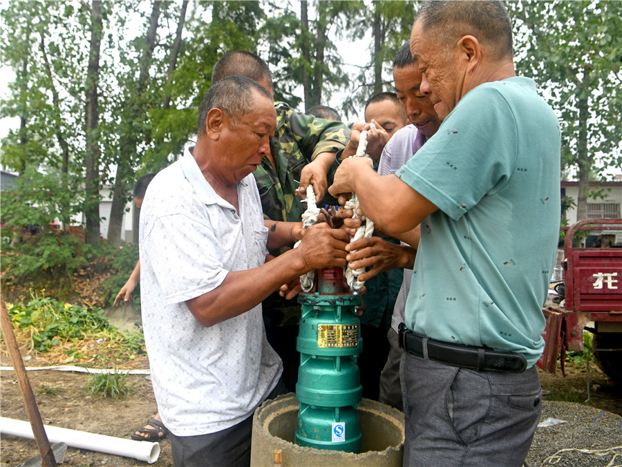 村民將新水泵放入剛打的井眼內，准備抽水灌溉。陳彬攝