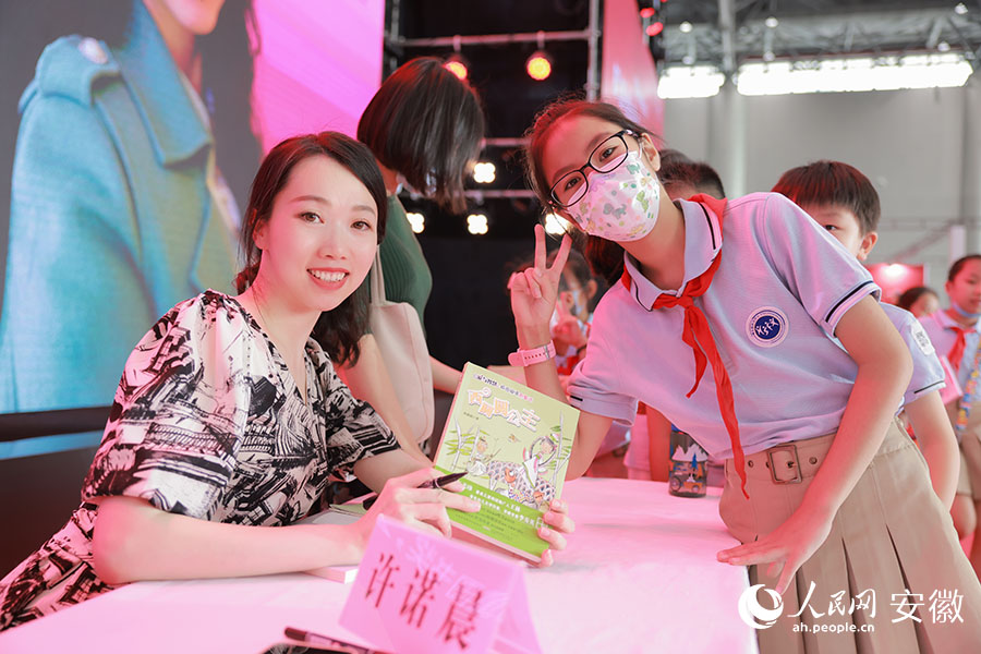 许诺晨与前来要求签名的小读者合影。人民网 王晓飞摄