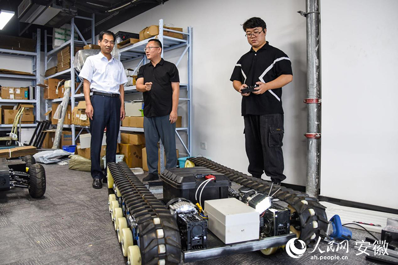 閆清泉（中）向黃敘新（左）介紹機器人產品。人民網 李希蒙攝