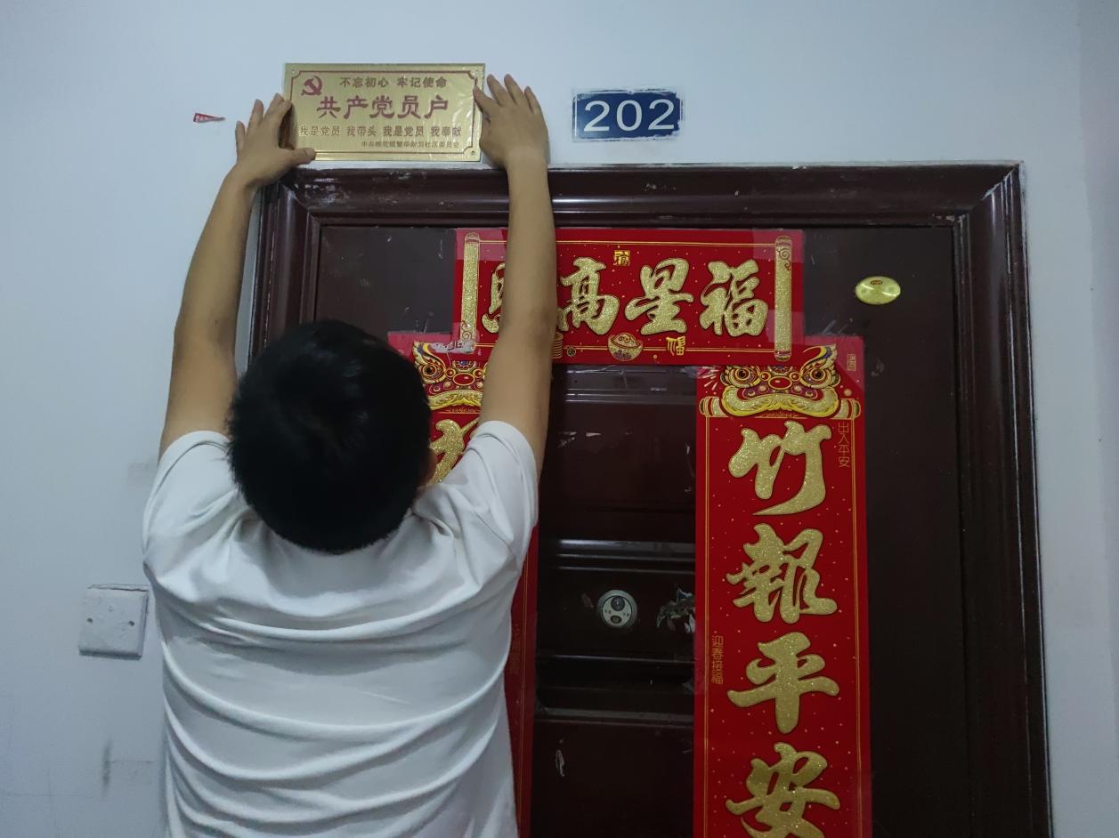 社区工作人员正在为一户党员家庭挂“共产党员户”标牌。蒋国慧摄