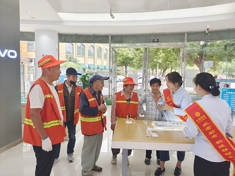 营业厅工作人员为环卫工人演示智能手机操作过程。安徽移动供图