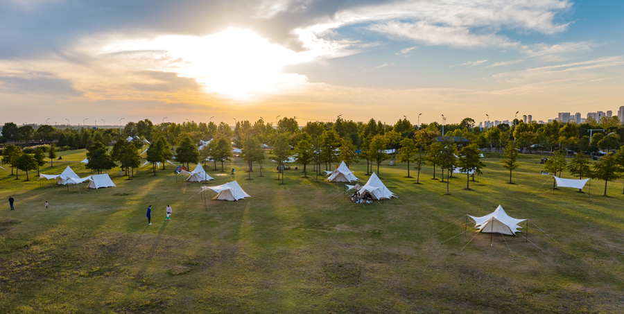 傍晚，市民在湖滨湿地公园的露营帐篷基地里休闲游玩。