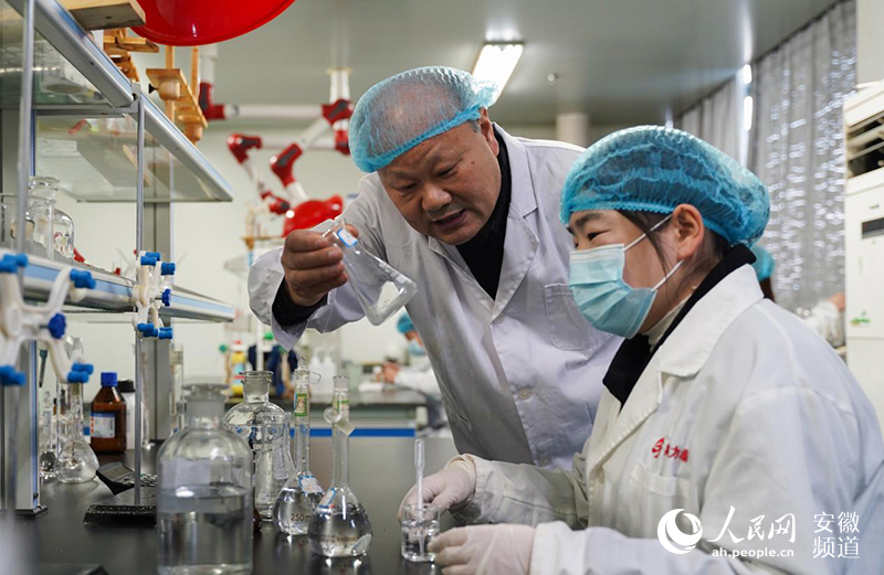 企業實驗室裡，馬峰（左一）正在同研究員討論藥品研制。人民網 王銳攝