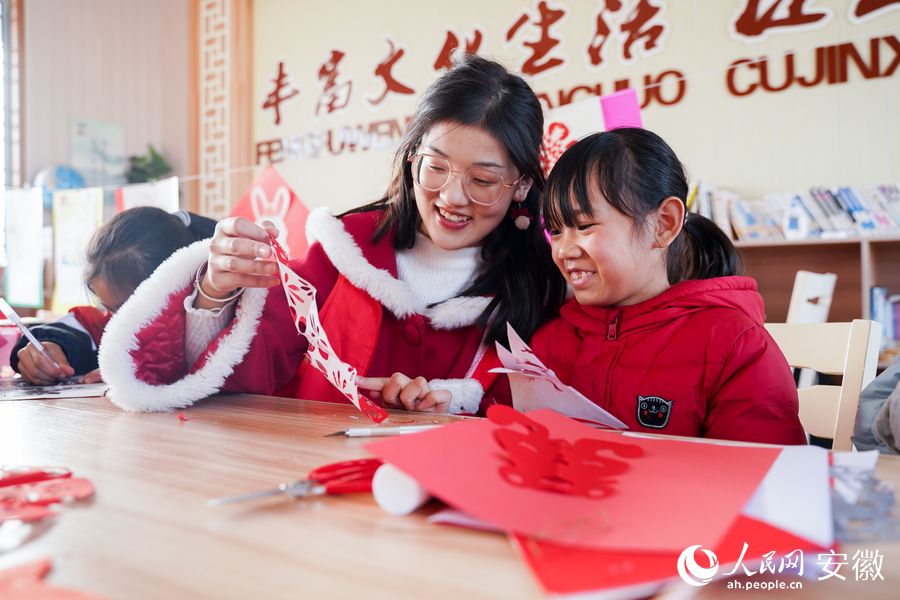 志愿者和留守儿童剪纸迎新春。人民网 王锐摄