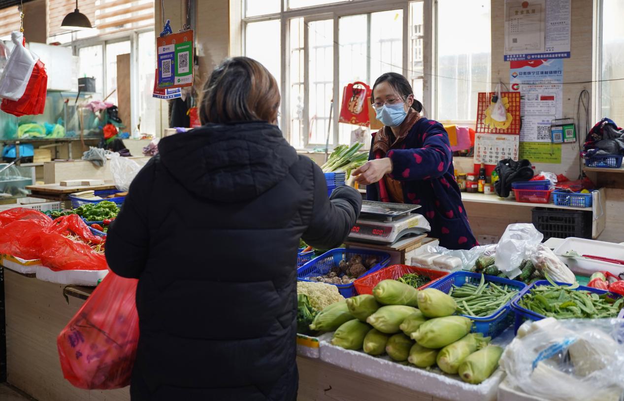 李春红（右）正在帮顾客称量。人民网 王锐摄