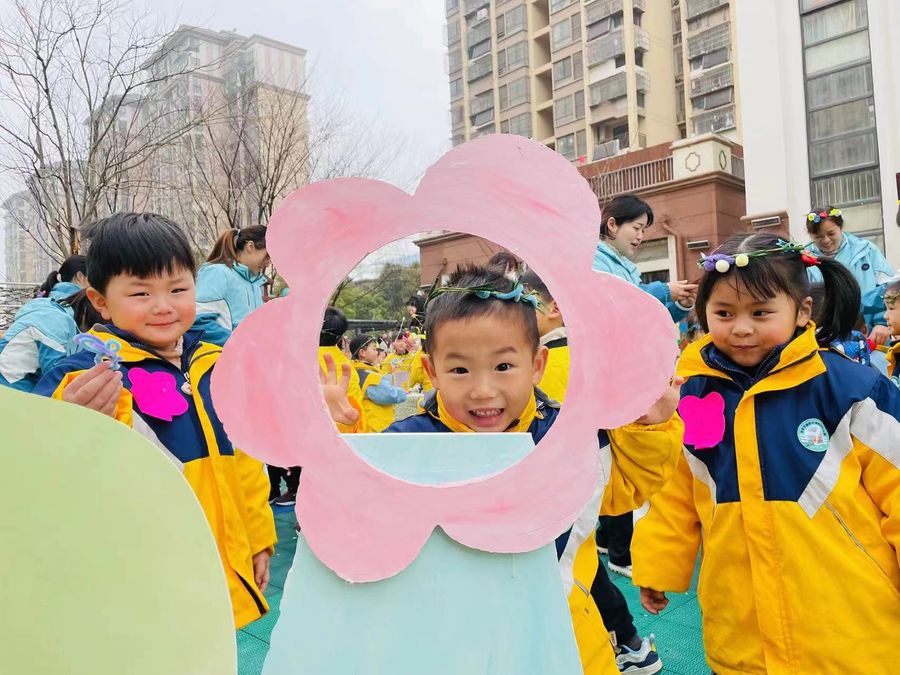 与花合影，孩子们在赏花、玩花中感知春天的美好。