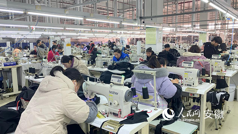 近百名工人正在操作台上缝纫、剪裁。人民网 吕欢欢摄