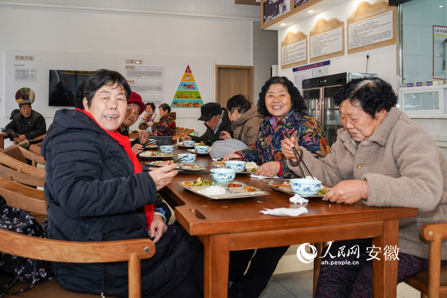 荣先兰（左一）正和“老姐妹”们在社区食堂里用餐。人民网 王锐摄