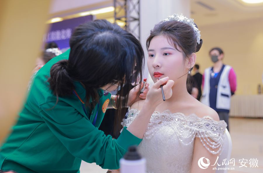 參加新娘化妝組競賽的選手在給模特化妝。人民網 王曉飛攝