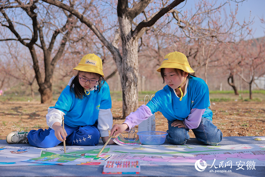 两位小朋友在乡村振兴百米长卷上涂鸦。人民网 王晓飞摄