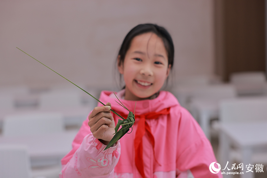 一位女孩展示自己编的蚱蜢。人民网 王晓飞摄