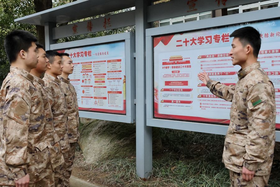 在训练间隙，县人武部参谋通过宣传展板向预定新兵宣讲党的二十大精神。沈云鹏摄