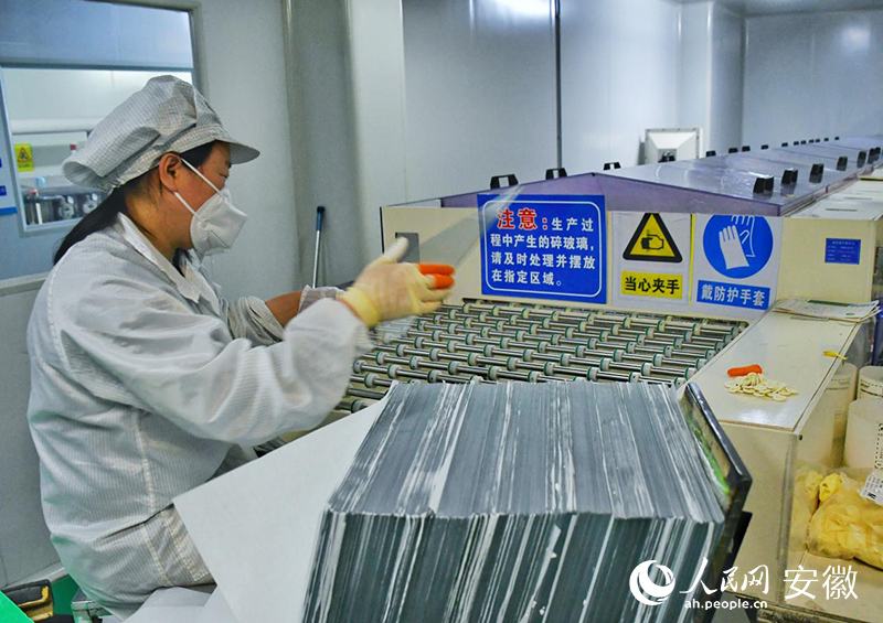 立光电子生产线上，工人正在检查玻璃。人民网 周坤摄