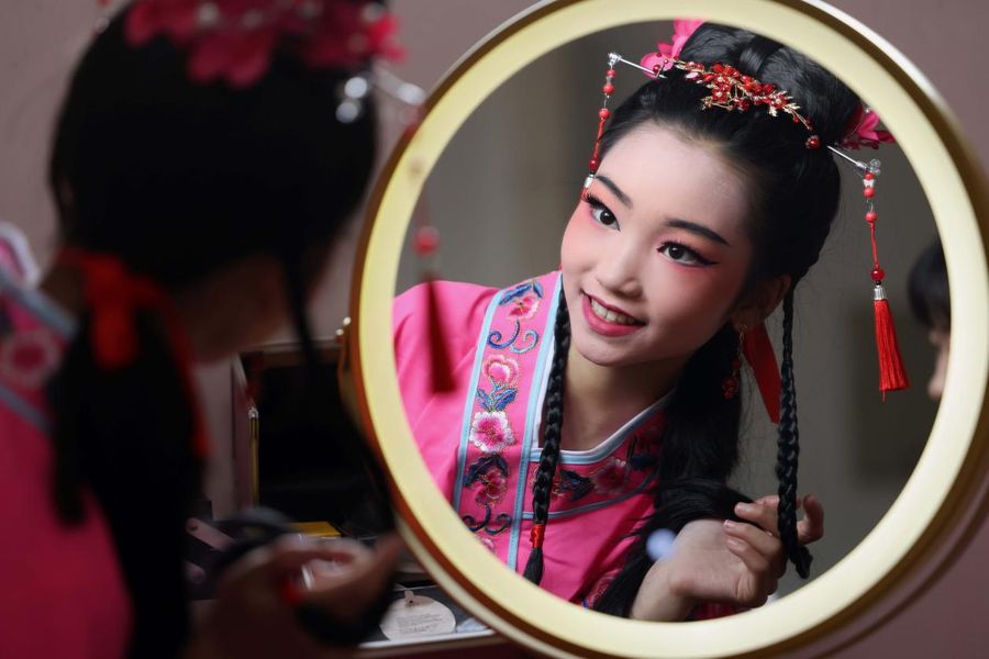 一名學習黃梅戲的孩子對著鏡子練習表情。
