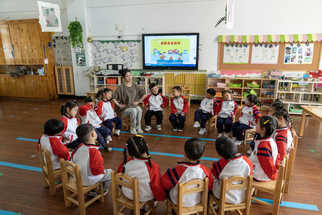 操场上，学生们体验跳竹竿、踩高跷、滚铁环等本土游戏