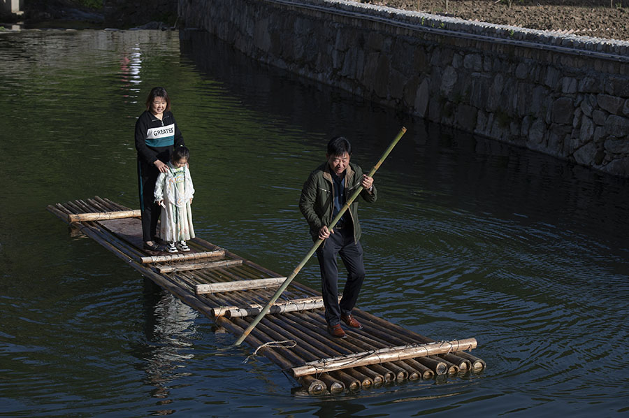 游客在桥下的溪水中划竹排。吴悦摄