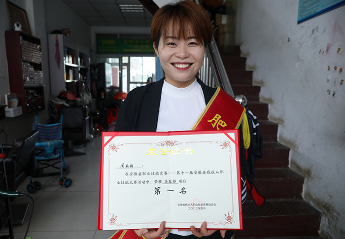 理发师周丽丽展示自己在省级技能比赛中的获奖证书。 陈家乐摄