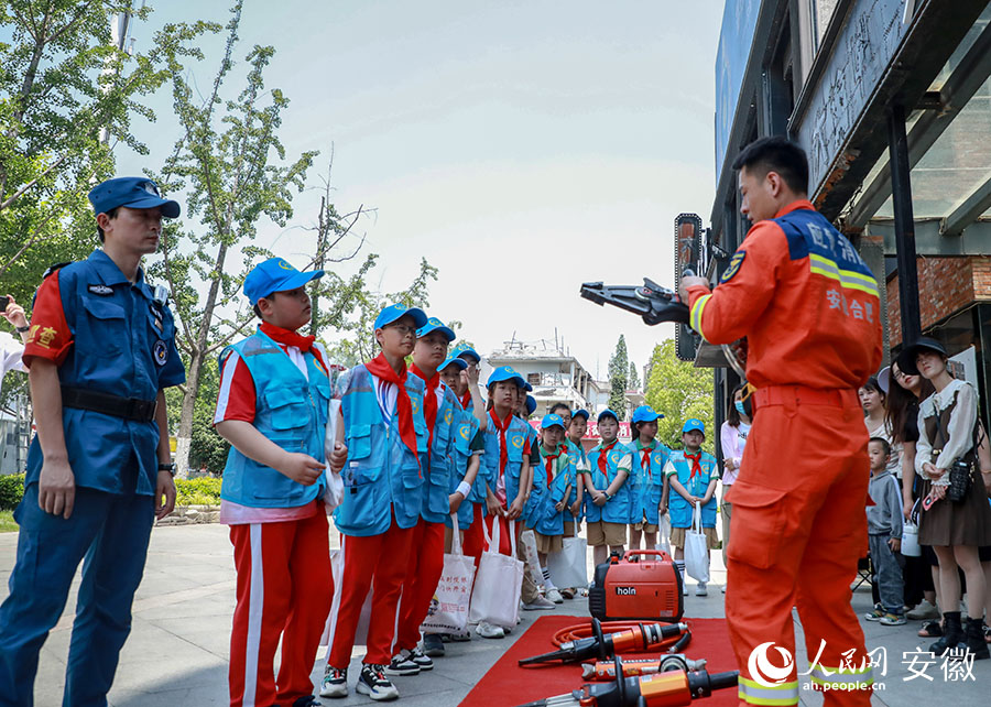 在微型消防站旁，一名消防隊員正在向小志願者們講解消防知識。人民網記者 陶濤攝