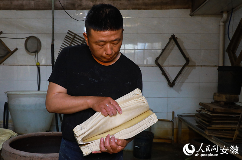 於学松师傅现场边制作边介绍，三和千张的制作工艺。人民网记者 陶涛摄