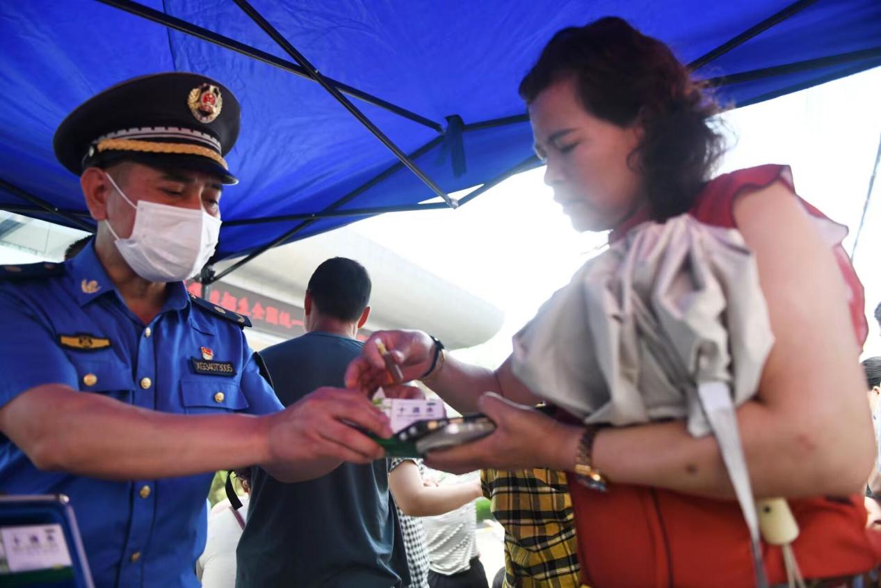 城管助考點工作人員向考生家長發放防暑降溫藥品。