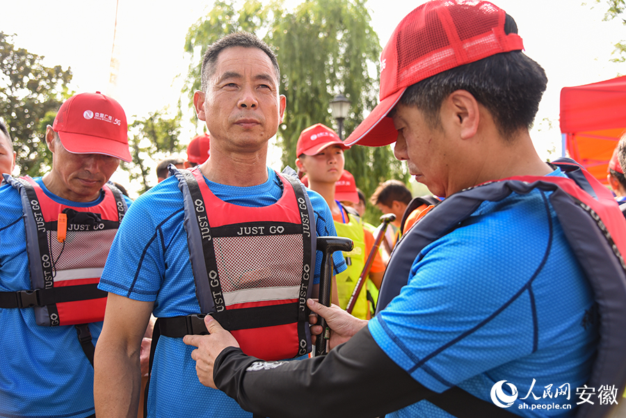 参赛选手在赛前互相检查救生衣。人民网 李希蒙摄