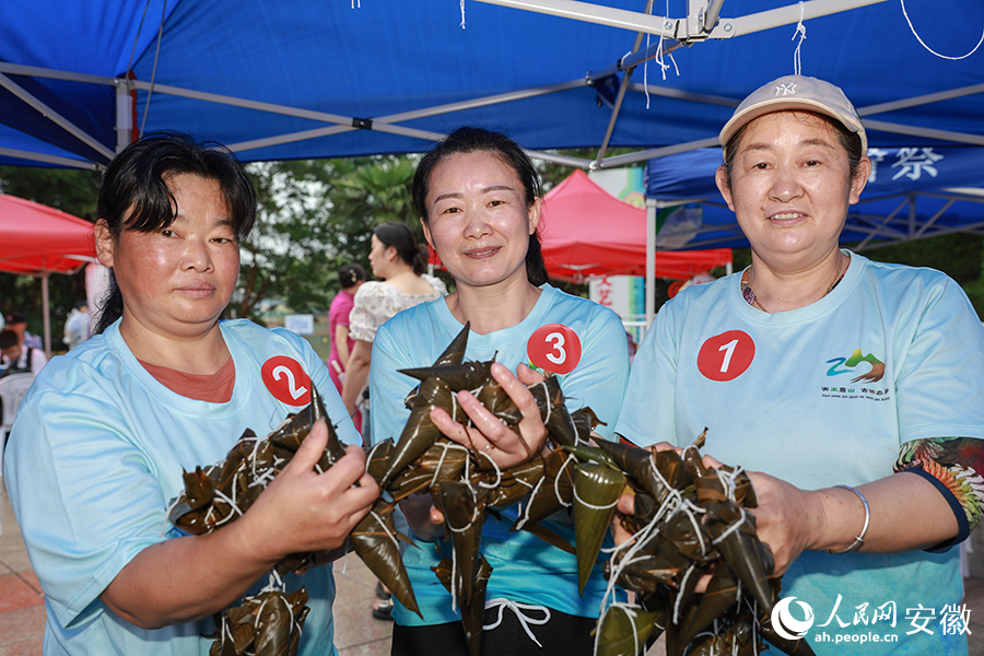 李平（右）和队友们捧起包好的粽子。人民网记者 张俊摄