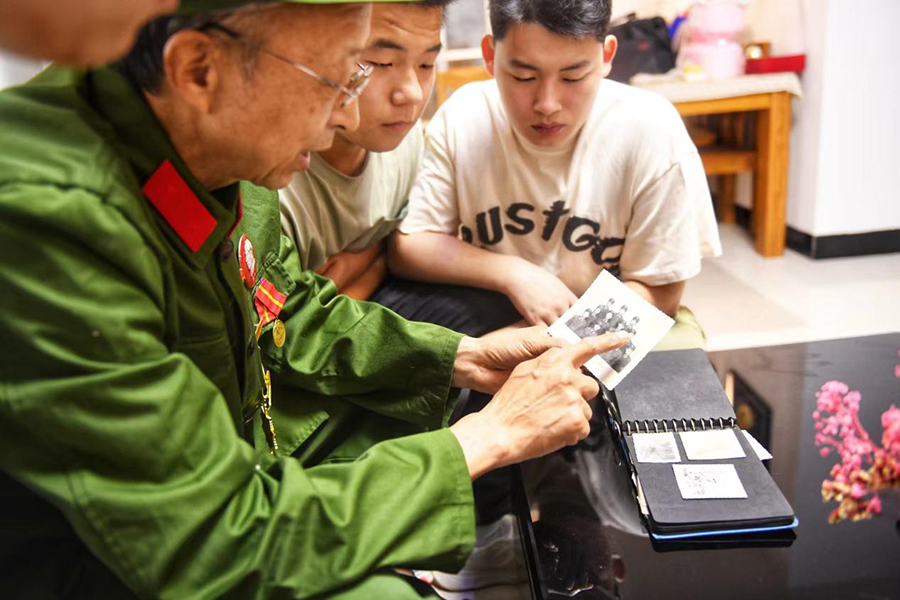 老兵为应征青年讲述老照片背后的战斗故事。秦龙供图