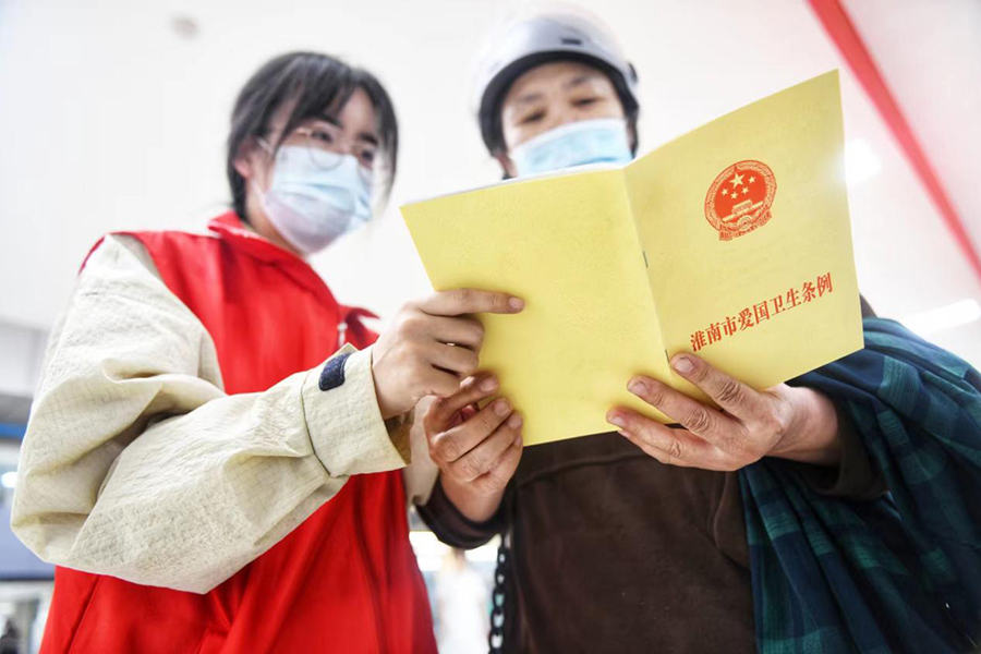 志愿者向群众宣传《淮南市爱国卫生条例》。秦龙供图