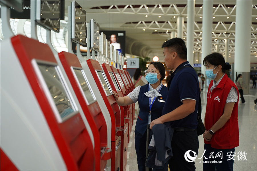 合肥新桥国际机场内工作人员正在指导旅客购票取票。人民网记者 王锐摄