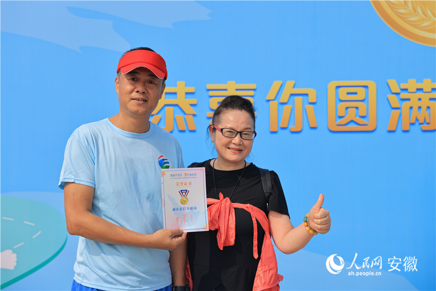 參與人員完成健步走后拿著証書打卡留念。人民網記者 王曉飛攝